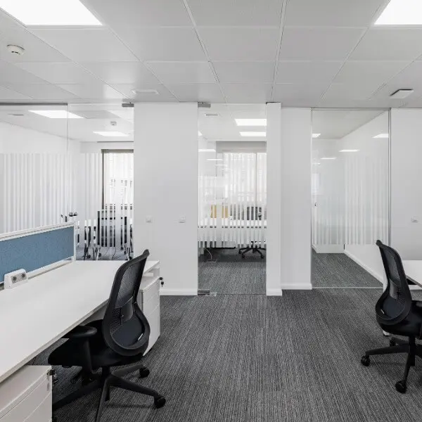 Modern, minimalist office workspace with glass partitions and clean white walls, professionally finished by Paint It Right.
