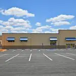 Freshly completed commercial exterior painting in Ann Arbor MI showcasing tan masonry and blue awnings on a modern retail building.